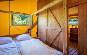 Vista interior de una cabaña de madera con cama doble en Safarilodge Deluxe, Papillon Country Resort, Países Bajos.