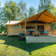 Solrigt billede af Safarilodge Deluxe med overdækket terrasse, grill og grønne omgivelser i naturen.