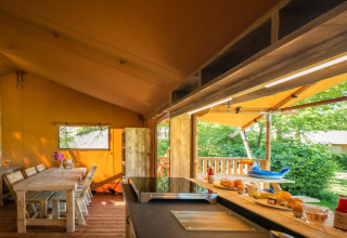 Indendørs og udendørs spiseplads i Safarilodge Deluxe ved Papillon Country Resort, omgivet af natur.