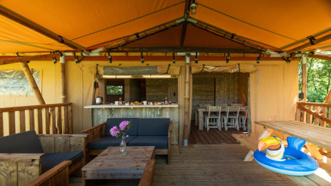 Udendørs opholdsområde i Safarilodge Deluxe, Papillon Country Resort, med træmøbler og pool-legetøj.