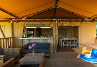 Overdekte buitenruimte van de Safarilodge Deluxe bij Papillon Country Resort met houten meubels.