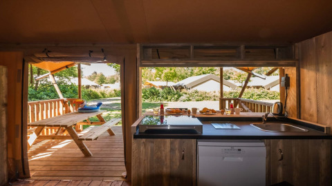 Vista desde la cocina de Safarilodge Deluxe en Papillon Country Resort, con terraza y banco de picnic afuera.