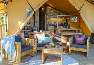 Gezellige Safari tent Premium bij Papillon Country Resort, Nederland, met houten zit- en eetmeubilair.