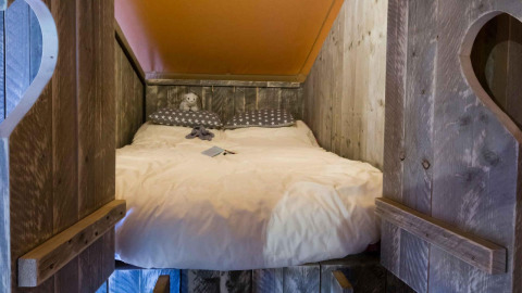 Coin nuit douillet en bois avec lit double dans la Safari tent Premium au Papillon Country Resort.