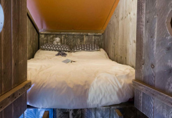 Gezellige slaapruimte met houten muren en bed in Safari tent Premium bij Papillon Country Resort.