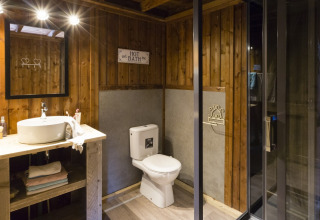 Baño del safari-tienda Spotty Lodge Family en Papillon Country Resort, Países Bajos, con paredes de madera y ducha moderna.