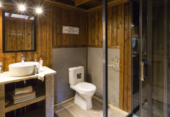 Baño del safari-tienda Spotty Lodge Family en Papillon Country Resort, Países Bajos, con paredes de madera y ducha moderna.