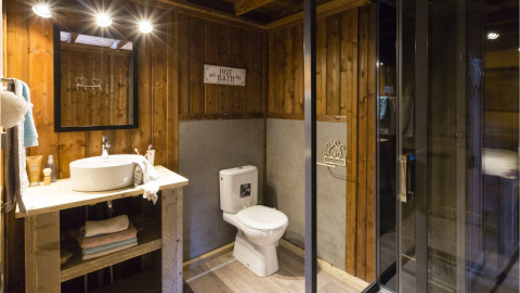 Baño del safari-tienda Spotty Lodge Family en Papillon Country Resort, Países Bajos, con paredes de madera y ducha moderna.