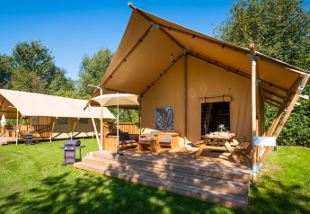 Zwei geräumige Safari-Zelte namens Spotty Lodge Family auf einer grünen Wiese, umgeben von Bäumen.