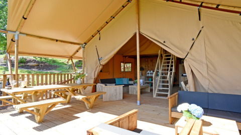Terraza de madera y acogedora sala de estar en tienda safari del Spotty Lodge Family en Papillon Country Resort.