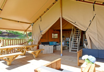 Ruime houten veranda en knusse woonkamer van een safaritent bij Spotty Lodge Family op Papillon Country Resort.