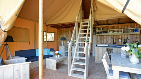Interieur van de Spotty Lodge Family safaritent bij Papillon Country Resort in Nederland, houten meubels.