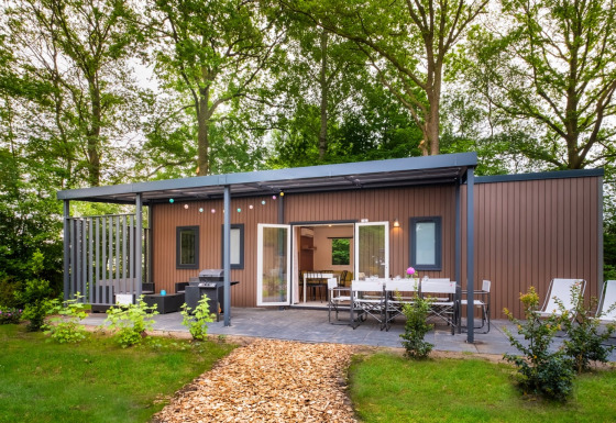 Cottage Next XXL Family-lodge på Papillon Country Resort, omgivet af træer og natur i Holland.