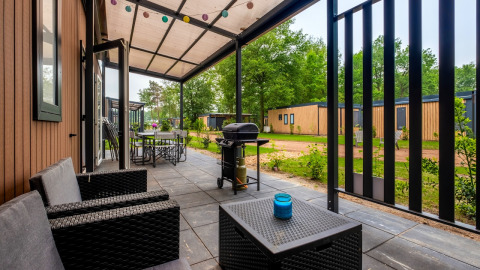 Überdachte Terrasse mit Sitzbereich und Grill im Cottage Next XXL Family im Papillon Country Resort Niederlande.