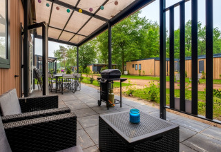 Overdekt terras met tuinmeubilair en barbecue aan Cottage Next XXL Family, Papillon Country Resort, Nederland.