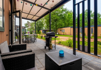 Patio coperto con area salotto e barbecue al Cottage Next XXL Family presso Papillon Country Resort, Paesi Bassi.