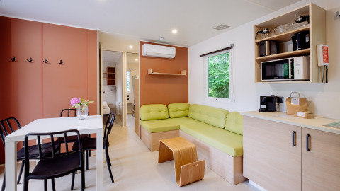 Acogedora sala de estar en Cottage Next XXL Family en Papillon Country Resort con sofá verde y cocina.