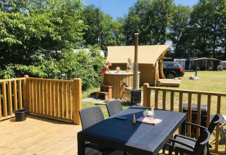 Terraza exterior con mesa, sillas y familia en jacuzzi en Airlodge 2.0 Family Hottub, Papillon Country Resort, Países Bajos.