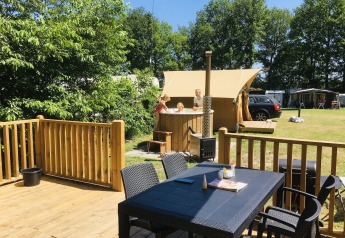 Outdoor deck with table, chairs, and family in hot tub at Airlodge 2.0 Family Hottub, Papillon Country Resort, Netherlands.