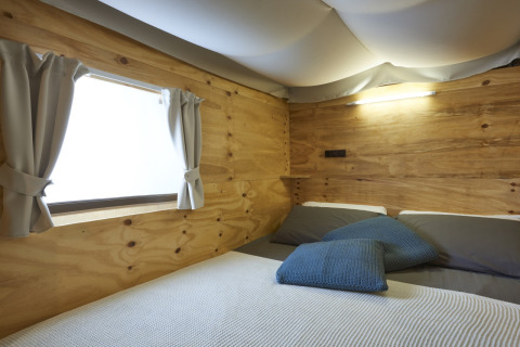 Chambre de l'Airlodge 2.0 Family Hottub au Papillon Country Resort avec murs en bois et fenêtre.