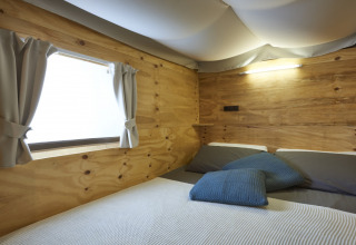 Chambre de l'Airlodge 2.0 Family Hottub au Papillon Country Resort avec murs en bois et fenêtre.