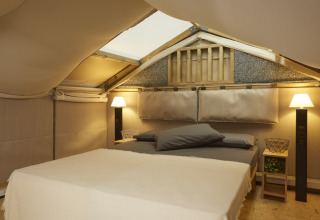 Dormitorio acogedor con cama y lámparas en Airlodge 2.0 Family Hottub, Papillon Country Resort, Países Bajos, bajo techo de tienda.