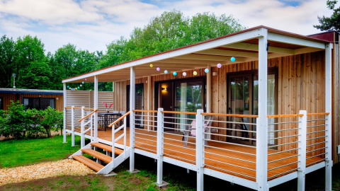 Vista exterior de la cabaña Cottage Next XL Luxury Superior con terraza de madera y luces de colores.