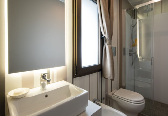 Moderne badeværelse med bruser, håndvask og spejl i Cottage Next XL Luxury Superior på Papillon Country Resort.