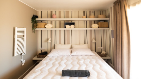 Gezellige slaapkamer met dubbel bed, schappen en manden in Cottage Next XL Luxury Superior in Nederland.