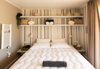 Moderne, komfortabelt soveværelse med dobbeltseng, hylder og dekorative kurve på Papillon Country Resort.