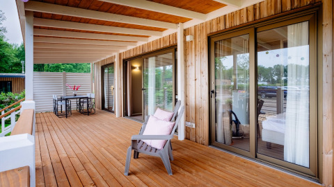 Amplia terraza de madera con sillón y mesa de comedor en Cottage Next XL Luxury Superior, Papillon Country Resort.