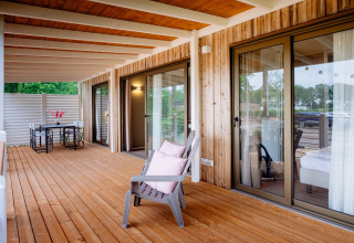 Amplia terraza de madera con sillón y mesa de comedor en Cottage Next XL Luxury Superior, Papillon Country Resort.