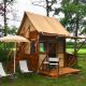 Tiny house called Airstay with wooden siding, small porch, chairs, and umbrella in a lush green yard.