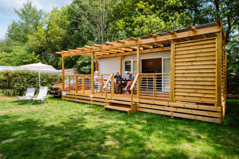 Cabane Cottage Next Midi au Papillon Country Resort aux Pays-Bas, avec des personnes assises sur la terrasse.