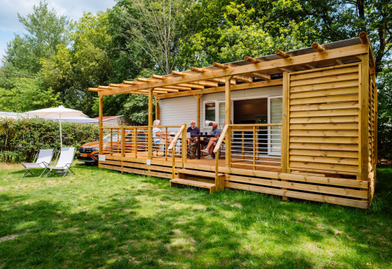 Cottage Next Midi al Papillon Country Resort nei Paesi Bassi, persone rilassate sulla veranda di legno.