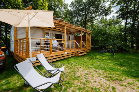 Charmant Cottage Next Midi au Papillon Country Resort avec terrasse en bois, transats et vélos à l’extérieur.