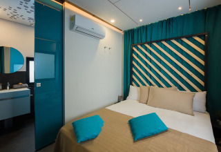 Modern bedroom at Freed Home in Papillon Country Resort, Netherlands, featuring teal accents and cozy bed.