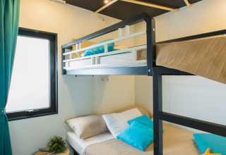 Chambre moderne avec lits superposés, coussins bleus et lumière naturelle à Freed Home au Papillon Country Resort.