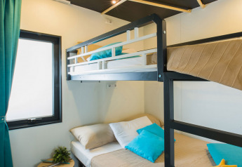 Moderne lodge-værelse med køjeseng, naturligt lys, blå gardiner og puder, på Freed Home i Nederlandene.