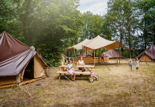 Gezinskamperen bij BreeBronne Vakantiepark in Limburg met tenten, tafels en kinderen spelend buiten.
