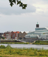 Vista de un moderno edificio y parque de vacaciones glamping junto al agua con casas coloridas detrás.