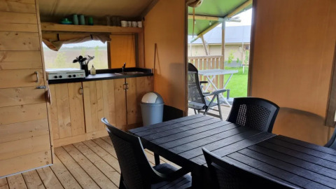 Interior of safari tent with kitchenette, dining table, and terrace at Boerderijcamping de Hinde, Netherlands.
