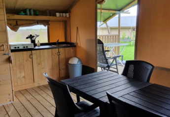 Interieur van safaritent met keukenblok, eettafel en terras bij Boerderijcamping de Hinde in Nederland.