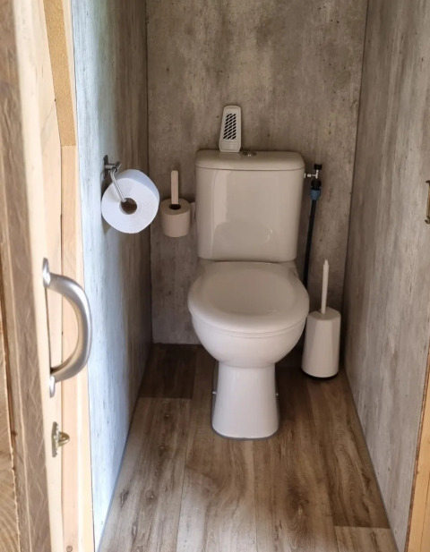 Kleines Bad mit Toilette und Holzboden in einem Safarizelt bei Boerderijcamping de Hinde, Niederlande.