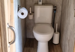 Kleine toiletruimte met houten vloer in een safaritent bij Boerderijcamping de Hinde, Nederland.