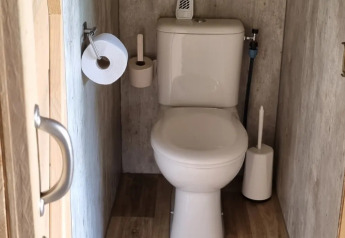 Un pequeño baño con piso de madera y sanitario moderno en una tienda safari en Boerderijcamping de Hinde, Países Bajos.