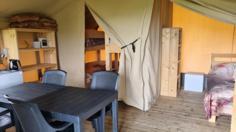Vista interna di una tenda safari al Boerderijcamping de Hinde nei Paesi Bassi, con letti e tavolo da pranzo.
