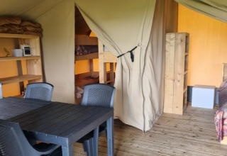 Binnenzicht van een safaritent bij Boerderijcamping de Hinde in Nederland, met bedden en eettafel.