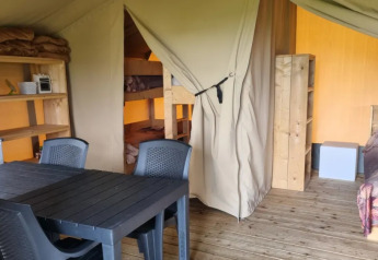 Vista interior de una tienda safari en Boerderijcamping de Hinde, Países Bajos, con camas y mesa comedor.
