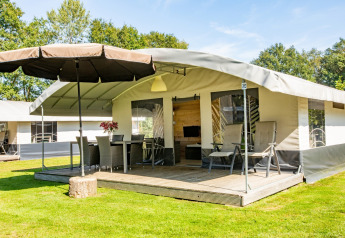 Safaritent met veranda, stoelen en parasol bij vakantiepark De Witte Berg in Nederland.